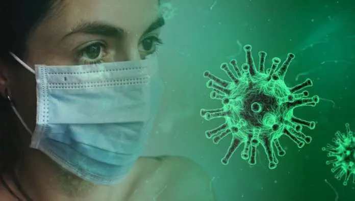 Una donna con la mascherina chirurgica accanto alla rappresentazione grafica del virus SARS-CoV-2