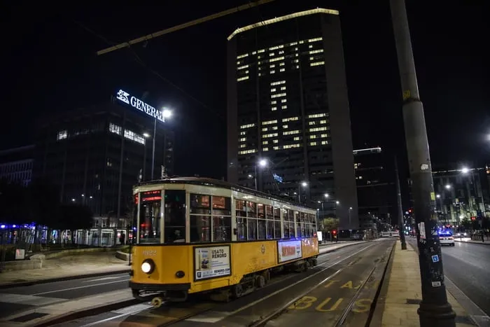 Un tram giallo in una via deserta di Milano di notte, durante il lockdown
