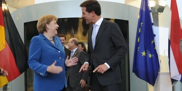 Angela Merkel e Mark Rutte conversano a margine di un vertice europeo, fra le bandiere nazionali